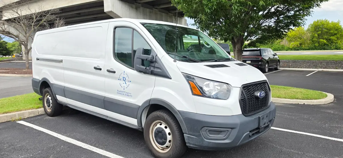 White Rush 24/7 Ford Transit cargo van with the blue compass logo and 24/7 dispatch phone numbers on the door